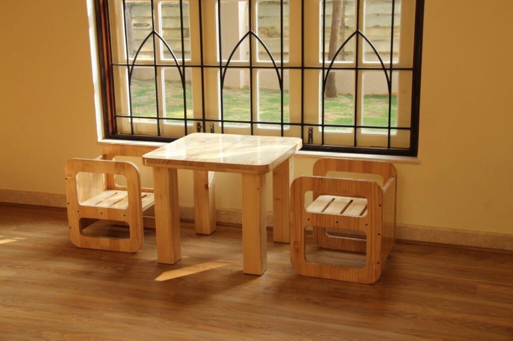 a room with a wooden table, chairs and a window  – Mont Ivy Preschools
