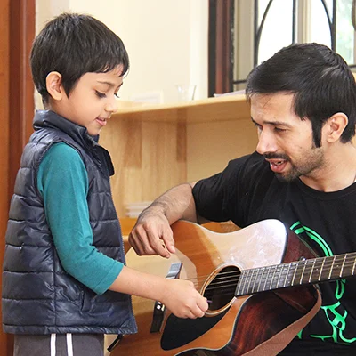 a man playing a guitar with a young boy – Mont Ivy Preschools